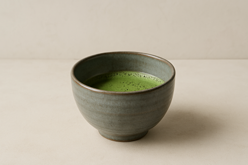 核心产品与质感	构图： 居中放置一个静谧、雅致的陶瓷抹茶碗（例如，灰蓝色或大地色釉面），碗中只有少许打好的抹茶，碗身有柔和的光线反射。背景简洁，体现侘寂（Wabi-Sabi）美学。	极简美学，高品质零售品